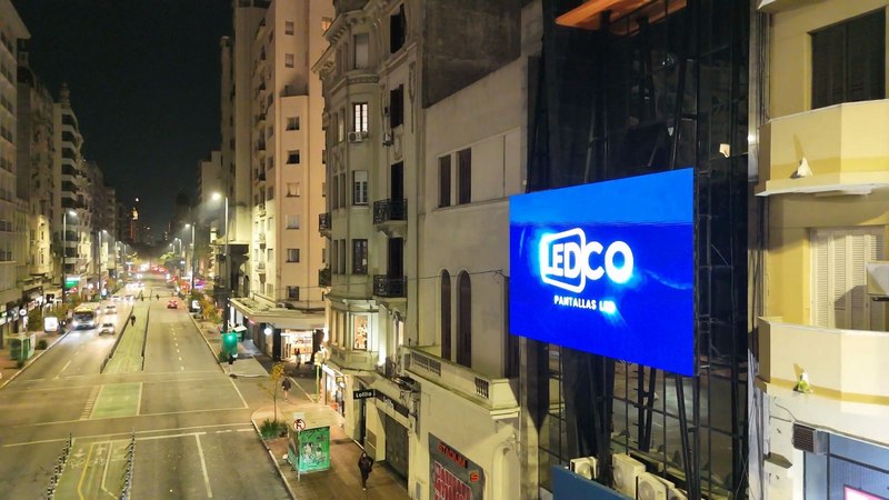 Pantalla LED de LEDCO encendida de noche sobre la avenida 18 de Julio, Montevideo