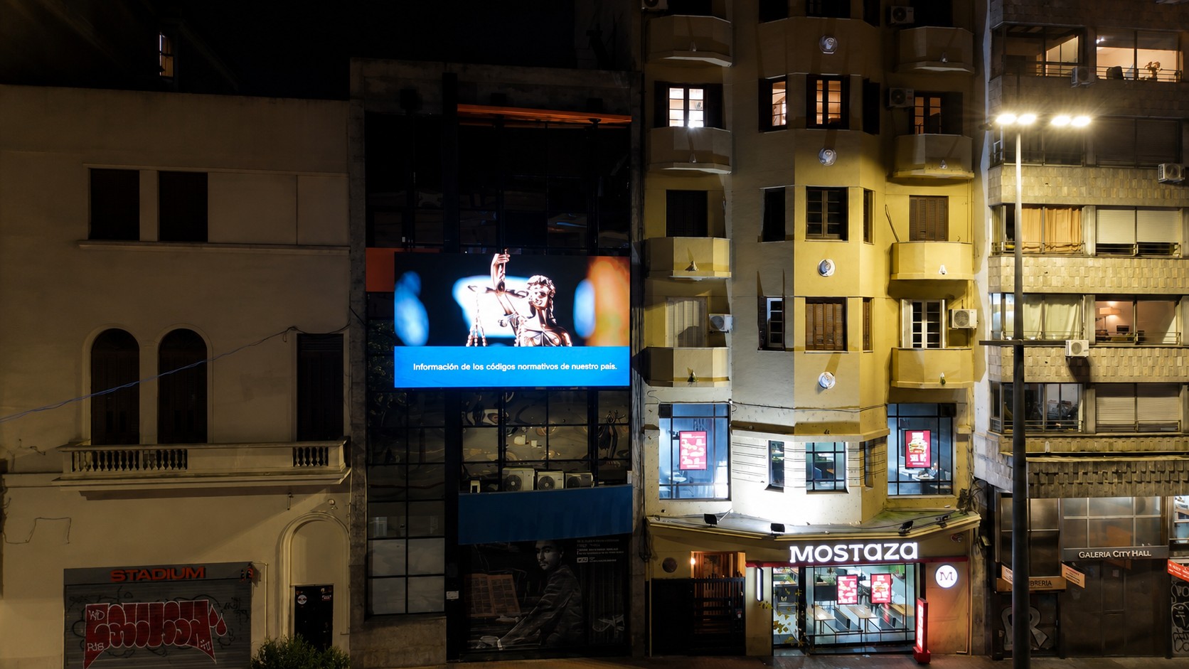 Pantalla LED exterior del IMPO mostrando una pieza institucional con la estatua de la Justicia